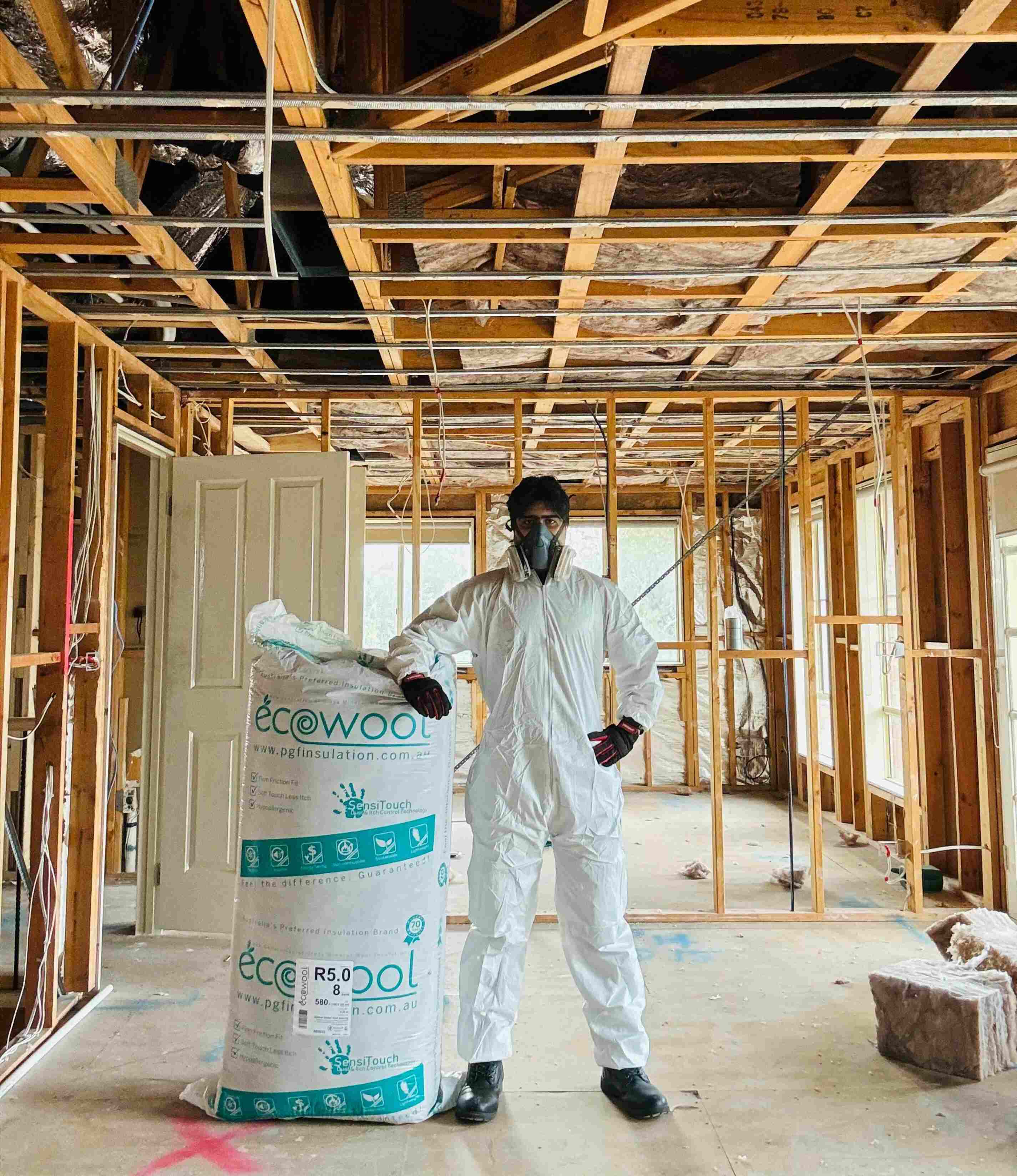 Insulation installer with glasswool beneath timber ceiling framing